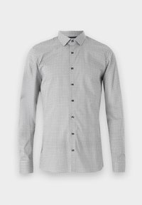 Camicia a maniche lunghe bianca e nera con motivo geometrico, abbottonatura frontale e colletto classico. Tessuto leggero con superficie liscia.