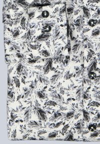 Weißer Stoff mit einem schwarzen und grauen Blattmuster, ausgestattet mit einer durchgehenden Knopfleiste, zwei Taschen und dunklen Knöpfen. Texturierter Rippstoff.