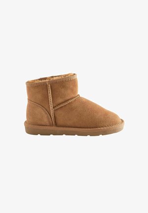 Bottine en daim tan avec un bout rond, doublure intérieure douce et semelle en caoutchouc. Présente un design cousu et un profil minimaliste.