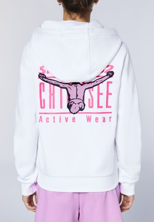 Person wearing a white hoodie with pink text "CHI DG SEE Active Wear" and a graphic of a person stretching arms wide on the back, paired with pink pants.
