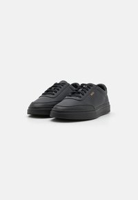 Schwarze Sneakers mit einer glatten, matten Lederoberfläche. Runde Zehen, flache Sohle und kontrastierende Nähte. Verfügt über schwarze Schnürsenkel und Branding an der Seite.