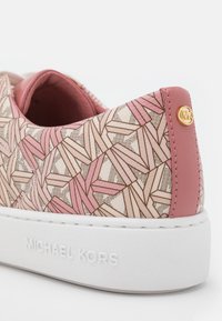 Talons de baskets rose et beige à motif avec un design géométrique, semelle blanche embossée de "Michael Kors," et bouton logo MK en or.