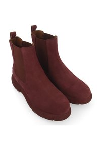 Bottines en daim bourgogne avec des panneaux latéraux élastiques, bouts ronds et semelle en caoutchouc texturé. Elles sont équipées de tirants sur chaque talon pour un enfilage facile.