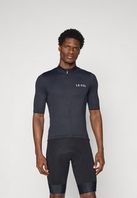 Maillot de cyclisme noir à manches courtes avec un col haut et une fermeture éclair frontale, arbore le logo "LE COL" sur la poitrine. Design texturé et ajusté.
