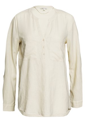 Blouse en lin crème à manches longues avec col rond, patte de boutonnage à trois boutons et deux poches poitrine.