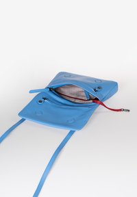 Borsa a tracolla blu in pelle con due zip, linguetta rossa a contrasto e fodera con motivo geometrico. Presenta un design piatto e due tracolle.