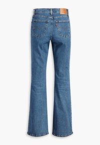 Jeans de mezclilla azul acampanados con una cintura de media altura, dos bolsillos traseros y un parche de cuero con la marca en la cintura. Detalles de costura clásica.