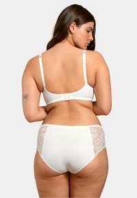 Soutien-gorge blanc et culottes taille haute avec des accents en dentelle sur les côtés. Tissu lisse, bretelles réglables et fermeture à crochet sur le soutien-gorge.