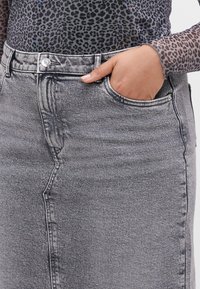 Gonna di jeans grigia scolorita con taglio dritto, dotata di tasca frontale, passanti per cintura e chiusura con bottone metallico in vita.