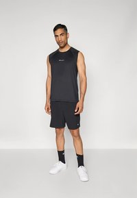 Mustade spordisärkide ja lühikeste pükstega komplekt, mis on valmistatud kergekaalus materjalist. Seljas on särk ja lühikesed püksid, millel mõlemal on logo. Komplektil on valged tossud ja tumedad sokid.