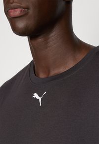 Black t-shirt with a crew neckline and short sleeves, featuring a white Puma logo on the left chest area. Smooth, cotton-like texture.