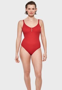 Costume da bagno intero rosso con spalline sottili, scollatura a V e zip frontale. Tessuto liscio e design aderente.