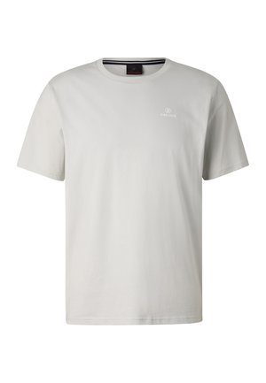 Person mit kurzen blonden Haaren trägt ein weißes T-Shirt mit schwarz-weißen Fotoaufdrucken von Wüste und Gleitschirmfliegen auf dem Rücken.