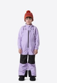 Μωβ χιονοστολή με μαύρες λεπτομέρειες, φερμουάρ μπροστά και ρυθμιζόμενους ιμάντες. Συνδυάζεται με κόκκινο και πορτοκαλί σκουφάκι με πομ πομ.