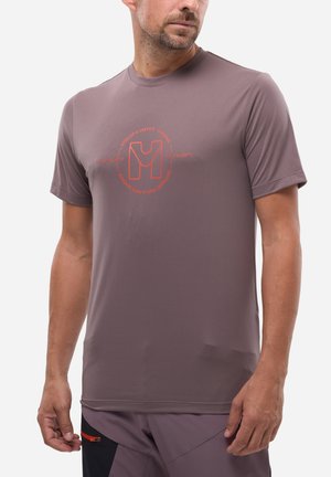 Homme portant un t-shirt de sport mauve à manches courtes avec un logo rouge sur la poitrine et un short mauve avec un panneau noir et une poche zippée.