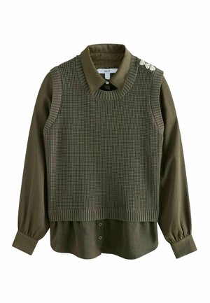 Chemise à manches longues vert olive foncé avec gilet en tricot sans manches assorti, décoré de trois boutons décoratifs sur l'épaule gauche.