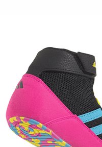 Botte de sport montante avec tige en maille noire, talon en suède rose, rayures bleu clair et semelle à motifs multicolores. Sangle ajustable à la cheville.