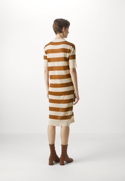 Rochie tricotată cu dungi orizontale alternating între maro și crem, având un decolteu circular și mâneci scurte. Material texturat.