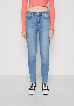 Hellblaue Jeans mit schmalem Schnitt, featuring eine hohe Taille, Fünf-Taschen-Design und Knopfleiste. Kombiniert mit schwarz-weißen Sneakers.