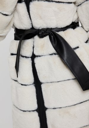 Abrigo de piel sintética blanca con rayas negras, que presenta un cinturón de cuero negro y cierre frontal con cremallera. Textura suave y secciones acolchadas.