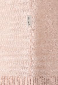 Helles rosa Sweatshirt mit einer weichen, strukturierten Oberfläche. Vertikales Rippenmuster, mit einem kleinen, gewebten Etikett an der Seite.