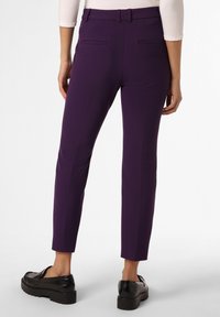 Fioletowe spodnie taliowane o gładkiej fakturze, slim fit, z szlufkami na pasek i kieszeniami z tyłu, zestawione z czarnymi loafersami na platformie.