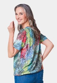 Kurzärmliges Oberteil mit einem mehrfarbigen abstrakten Muster in lebhaften Rottönen, Grüntönen und Blautönen. Hergestellt aus leichtem, strukturiertem Stoff.