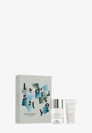 Coffret cadeau parfum comprenant un flacon en verre transparent avec un bouchon argenté et un tube blanc ; emballé dans une boîte vert clair avec des accents géométriques.