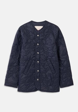 Tengerészkék steppelt dzseki kerek nyakkivágással, nagy elülső zsebekkel és patent gombos záródással. Az egész felületén kiemelkedő virágmintázattal rendelkezik.