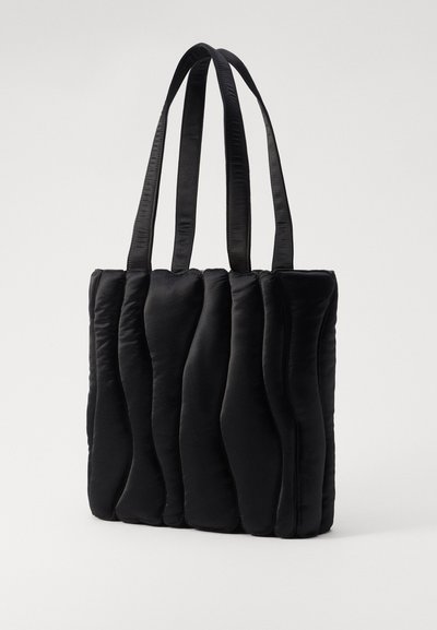 Sac fourre-tout noir matelassé avec une texture douce et rembourrée, doté de deux poignées en satin robustes et d'une forme rectangulaire.