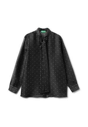 Schwarze Bluse mit langen Ärmeln und weißen Polka Dots, hohem Kragen und gebundenem Halstuchdetail, flach auf weißem Hintergrund ausgelegt.