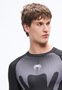 Czarna sportowa koszulka o dopasowanym kroju, z gradientowym szarym wzorem i centralnym logo. Gładka faktura i okrągły dekolt.