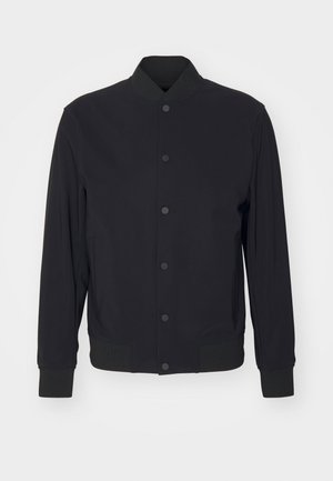 Must must välja bomber jakk, millel on klõpsuga esiosa, soonikkoes krae, mansetid ja vöökoht, esitatud tavalise valge tausta ees.