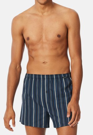 Gestreepte mannenboxershorts van lichtgewicht stof; heeft een blauwe basis met variërende lichtblauwe en grijze strepen, een elastische tailleband en een knoopsluiting aan de voorkant.