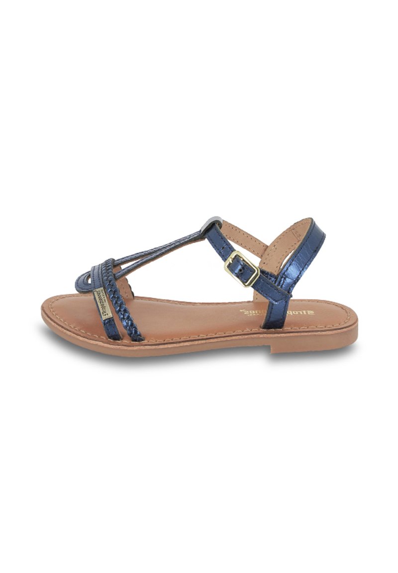 Sandalias planas azul marino con tiras trenzadas, detalles dorados y cierre de hebilla. Plantilla de cuero natural y suela delgada marrón.
