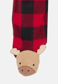 Rote und schwarze karierte Fleece-Socke mit einem beigefarbenen Tiergesicht an der Spitze, ausgestattet mit Ohren und ausdrucksvollen Merkmalen.