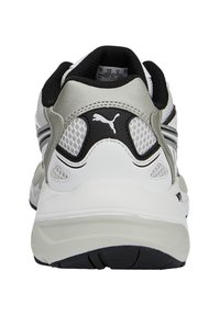Scarpa sportiva bianca e argento con forma arrotondata, pannelli in rete testurizzati, dettagli neri e un logo prominente sul tallone.