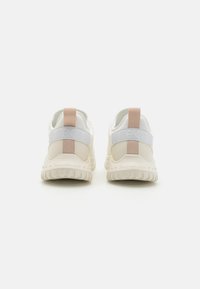 Beige joggesko med hvitt mesh og gummidetaljer. Har et rosa elastisk hælrem og teksturert gummisåle. Minimalistisk design.