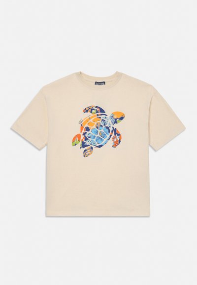 Beżowa koszulka z krótkim rękawem z kolorową grafiką żółwia morskiego wykonaną z kwiatowych i abstrakcyjnych wzorów, umieszczoną na środku przodu.