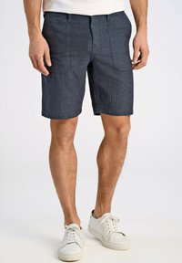 Jeansshorts i mörkblått, med ett strukturerat mönster, två framfickor och rak passform, parat med vita sneakers.