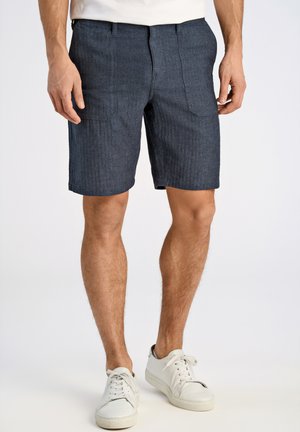 Dunkelblaue Jeans-Shorts mit einem strukturierten Muster, zwei Fronttaschen und geradem Schnitt, kombiniert mit weißen Turnschuhen.