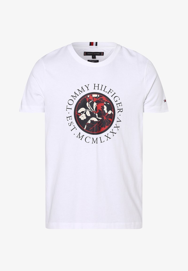 Camiseta de algodón blanca con un gráfico floral circular en negro y rojo que incluye el texto "TOMMY HILFIGER" y "EST. MCMLXXX". Mangas cortas.