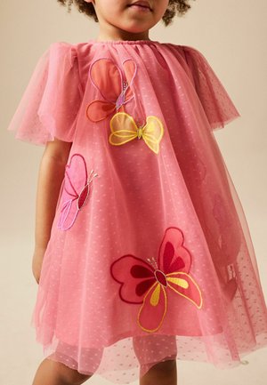 Copil purtând o rochie roz, transparentă, până la genunchi, cu mâneci bufante și o broderie mare, colorată, cu fluturi în față.