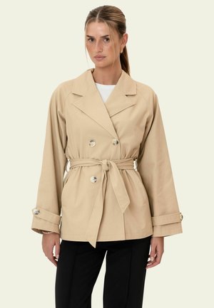 Trench bej cu dublu piept cu talie cu curea, mâneci lungi, accente cu nasturi argintii și un guler structurat. Textură netedă a materialului.