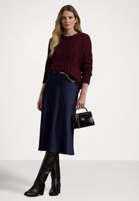 Bordó kábelmintás pulóver, tengerészkék midi szoknya, fekete magassarkú csizma és egy kis fekete krokodilbőr mintájú kézitáska arany részletekkel.