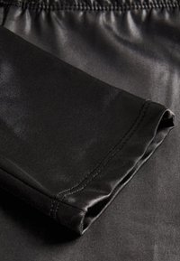 Tejido atlético negro con textura suave; cuenta con una cinturilla ancha y costuras planas, diseñado para la comodidad y el movimiento.