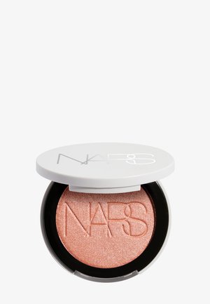 Poudre compacte ronde avec couvercle blanc partiellement ouvert, révélant une poudre pêche scintillante embossée du logo "NARS".