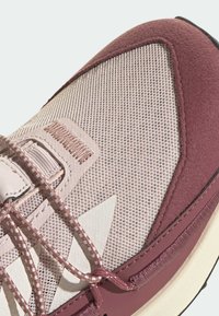 Baskets sportives bordeaux avec une tige en maille et des accents en daim, présentant des motifs texturés contrastants et des lacets plats. Design léger.