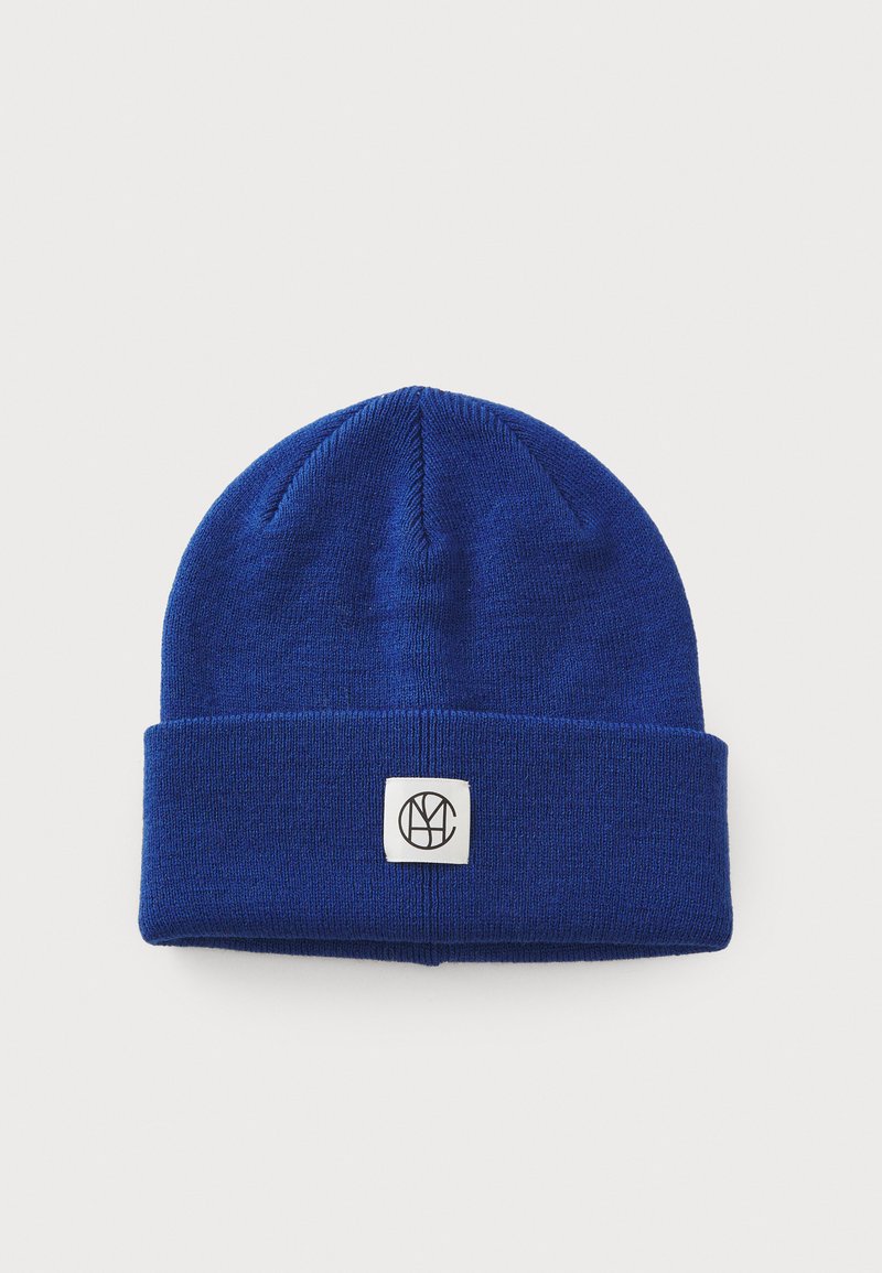 Blue knit beanie with a folded cuff, featuring a square tag with a black logo. Soft texture and classic design for warmth.