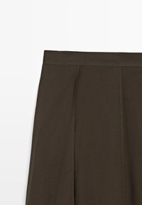 Gonna in tessuto marrone con un design plissettato, caratterizzata da una texture morbida e una vita alta. La gonna presenta bordi puliti e rifiniti.